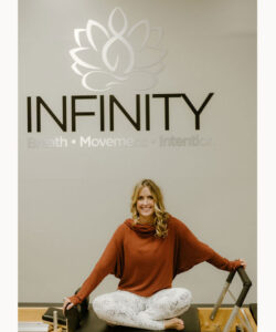Shannon Prestopine seated on equipment under Infinity logo on the wall